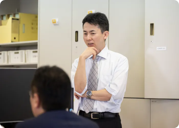 オフィスで社員に向けて説明を行うスーツ姿の男性