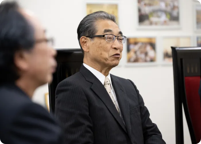 椅子に座り、対談するスーツ姿の男性