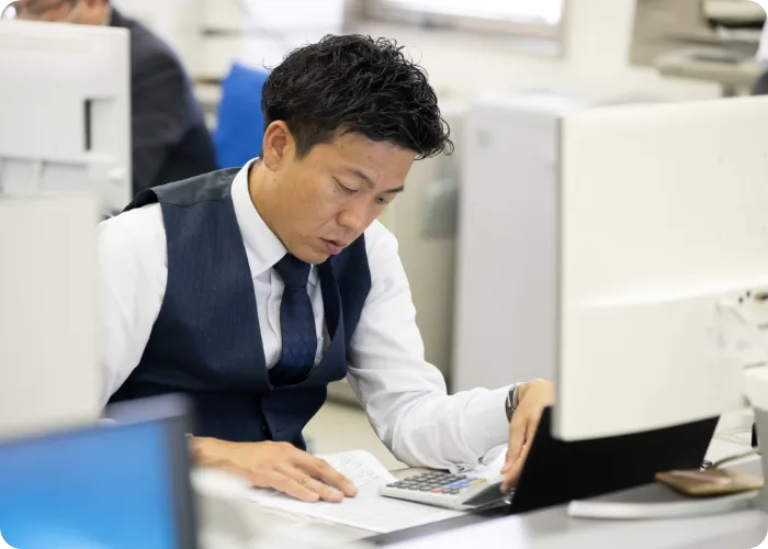 デスクで書類を見ながら作業する男性職員