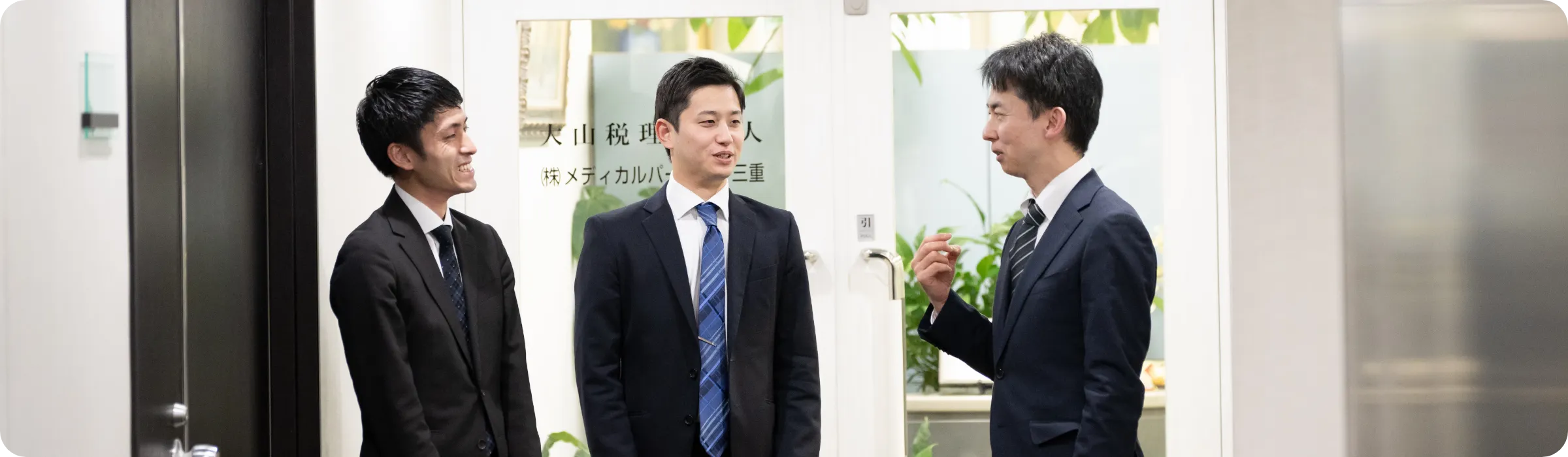 立って話し合う3人の男性職員