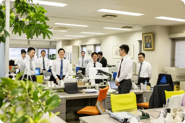 オフィスで起立する職員たちの様子