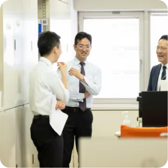 オフィスで立って話す3人の男性職員