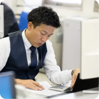 デスクで書類を見ながら作業する男性職員
